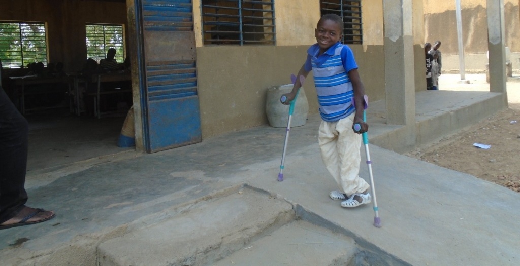 un enfant handicapé sur une rampe d'accàs pour entrer dans une classe