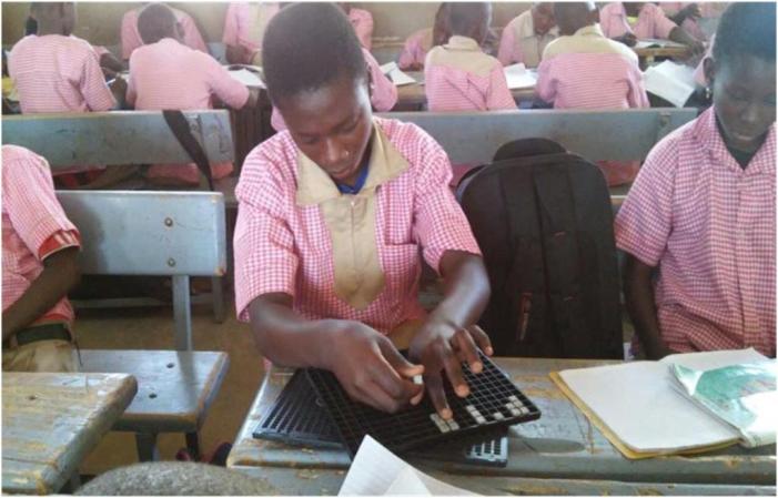 élève handicapé visuel entrain d'utiliser sa tablette et son poin¸on en classe