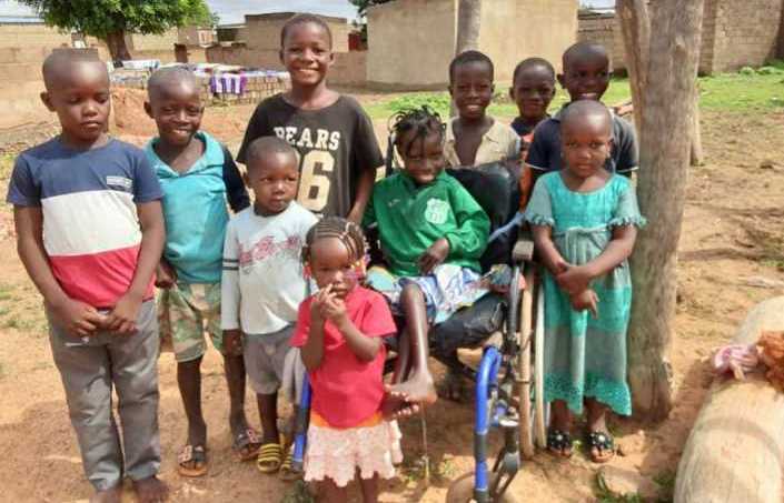 une petite fille handicapée dans son fauteuil roulant entourée par ses amis