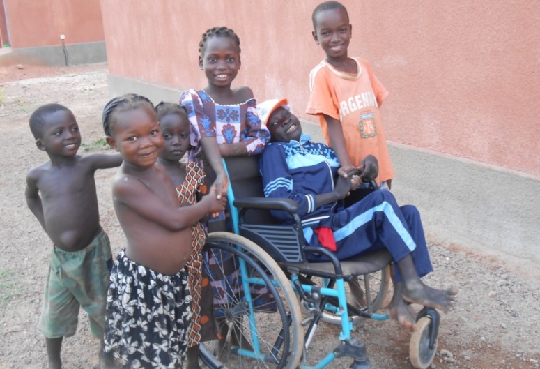 un enfant handicapé dans son fauteuil roulant entouré par ses amis