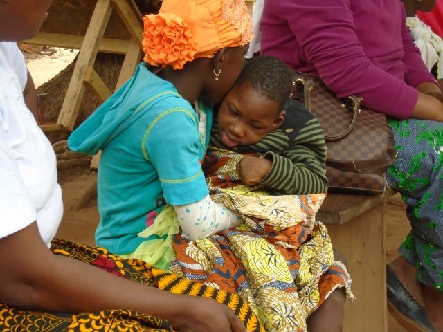 une fillette tenant dans ses bras un enfant qui dort