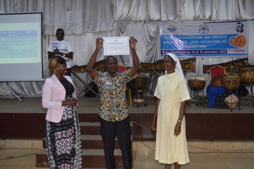 Le lauréat du concours de l'école
                                                                                                     la plus inclusive de la ville de Bobo Dioulasso
                                                                                                     première édition qui brandit son attestion de mérite
                                                                                                     à la cérémonie de proclamation des résultats