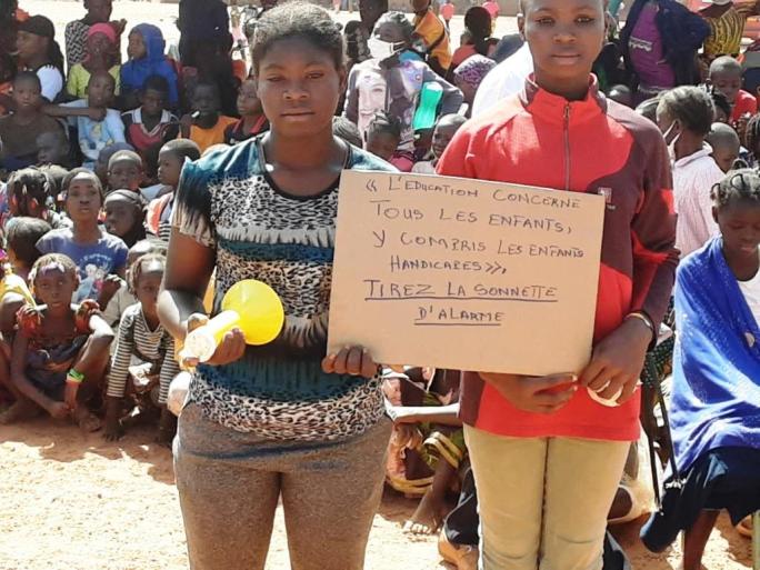 élèves portant une pancarte avec un slogan en faveur de
                                                                                               l'éducation inclusive lors de la sonnette d'alarme